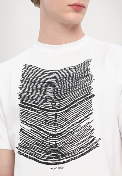 Balts īsām piedurkņu T-krekliņš ar melnu līniju dizainu, kas atgādina koka tekstūru. Apakšā ir drukāts teksts "WOOD WOOD".