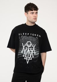 Black cotton t-shirt featuring a white graphic design with geometric patterns and the text "SLEEP TOKEN" above. Short sleeves and relaxed fit.