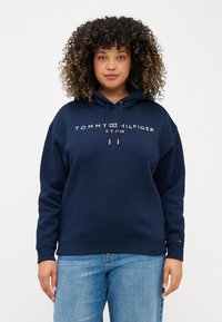 Felpa blu navy con cappuccio e cordino, caratterizzata dal logo "TOMMY HILFIGER" e dall'anno di fondazione. Tessuto morbido, vestibilità comoda, polsini e orlo a costine.
