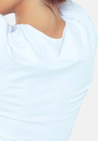 Jasnoniebieska, dopasowana koszulka z miękkiej tkaniny z delikatnym marszczeniem przy dekolcie z tyłu. Brak widocznych wzorów lub dodatkowych elementów.