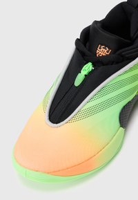 Sportssko med en gradient overdel fra orange til grøn, sorte mesh-detaljer, lynlås-lukning og tekstureret sål for godt greb.