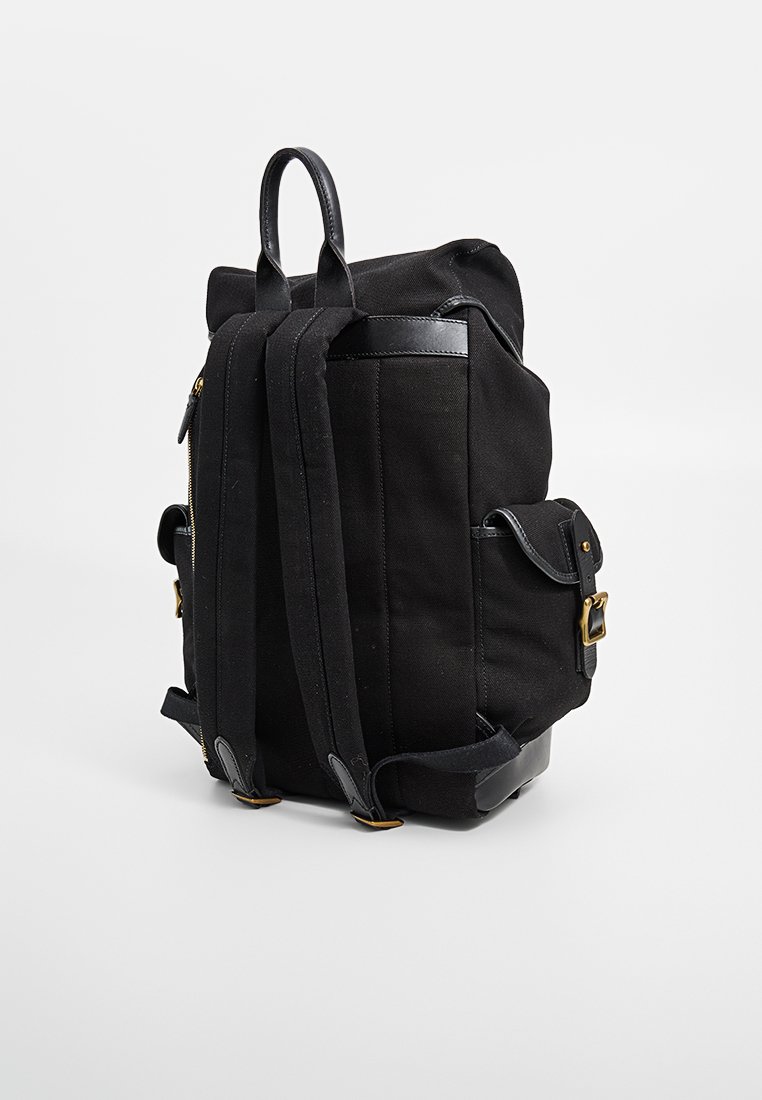 Schwarzer Canvas-Rucksack mit Lederakzenten, strukturierte Form, gepolsterte Schultergurte, Seitentaschen und eine verstellbare obere Verschluss.