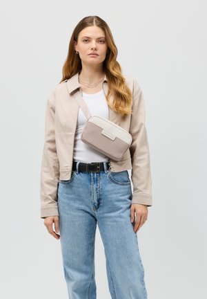Umhängetasche in Beige und Cremetönen, rechteckige Form, strukturiertes Material, mit einem dünnen verstellbaren Trageriemen und einem Logo-Patch auf der Vorderseite.