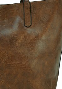 Bruine neplederen tote bag met een gladde, gestructureerde afwerking en een strakke vorm. Heeft een korte handgreep en een minimalistisch ontwerp.