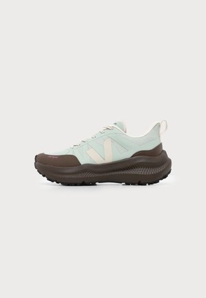 Ανοιχτό πράσινο και καφέ sneaker εκτός δρόμου με παχιά σόλα, λευκά κορδόνια, μεγάλο μπεζ λογότυπο "V" και ταινία έλξης στη φτέρνα, απεικονίζεται από το πλάι.