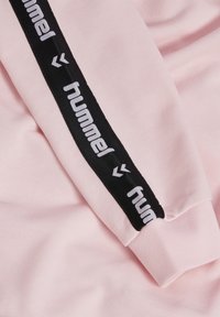 Roze sweatshirt met een zwarte stripes langs de mouw en witte 'hummel' branding. Zachte textuur met een getailleerd ontwerp.