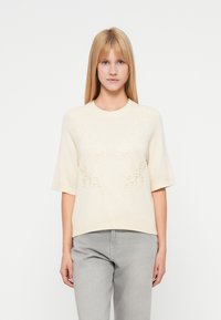 Pull crème à manches courtes avec broderie florale sur le devant, col et ourlet côtelés, fabriqué en tissu tricoté doux et texturé.