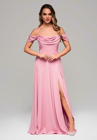 Lång rosa klänning med axelbandslösa ärmar, cowl-krage, hög slits och mjukt tyg. Matchas med ljusa klackar.