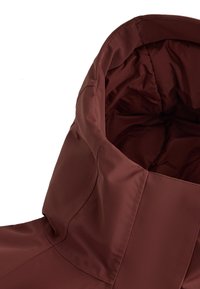 Bordo izolirana jakna z visokim ovratnikom, gladkim sintetičnim materialom in čistimi šivi. Notranjost je podložena za toploto.