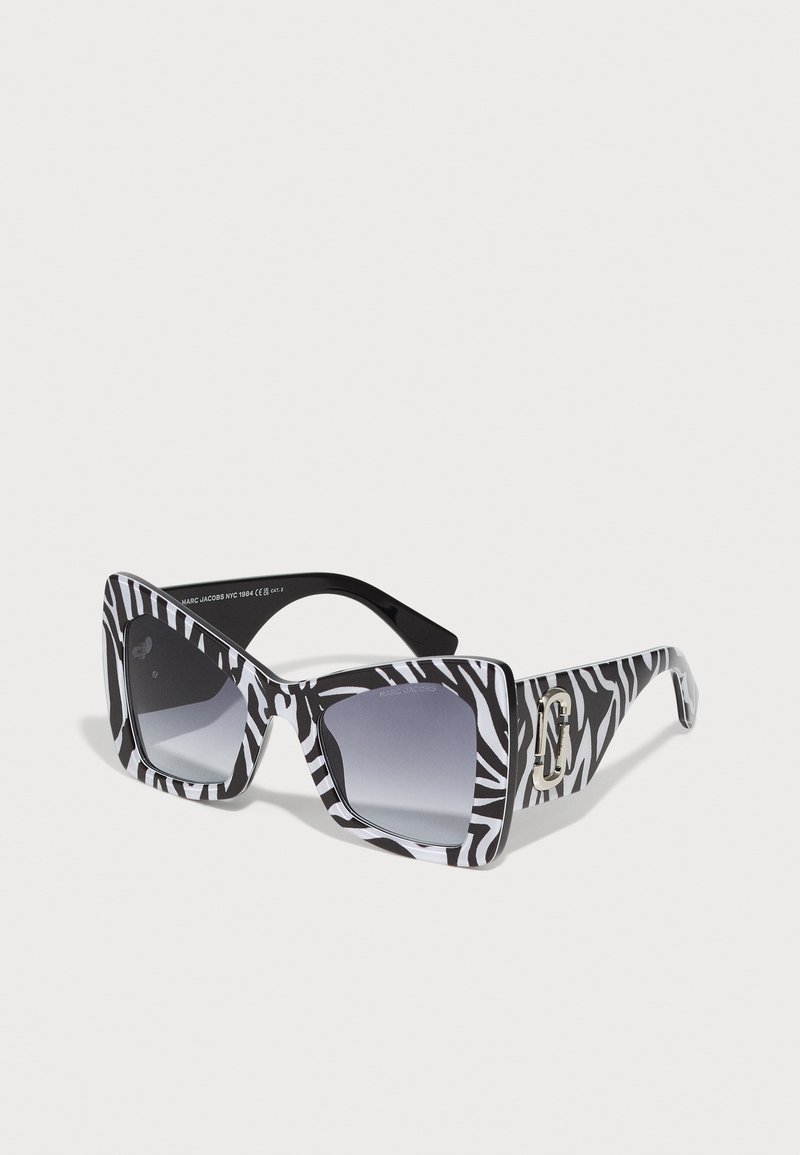 Zwart-witte zebra print zonnebril met een vierkante vorm, gradient lenzen en een zilveren logo-accent op de poot.