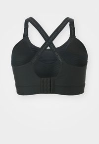Sostén deportivo negro con tirantes en forma de cruz, fabricado en tejido suave, con un diseño texturizado y cierre a presión con ganchos ajustables en la parte posterior.
