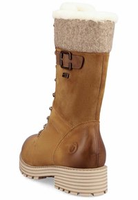 Botín de ante marrón con un puño de lana beige texturizada, parte delantera con cordones, detalle de hebilla y suela de goma estriada para mayor tracción.
