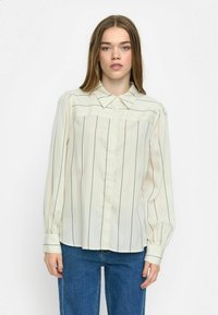 Lichtbeige overhemd met zwarte verticale strepen, voorzien van een kraag en lange, opgezette mouwen. Zachte, lichte stof.