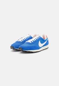 Blue mesh sneakers with suede accents, white laces, and a white swoosh logo. Red heel detail and black rubber outsole. Classic running design.