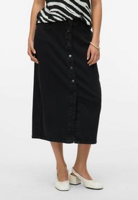 Črna denim midi krila s sprednjimi gumbi, ravnim krojem in stranskimi žepi. Ujemajoča se s črno-belim vzorčastim zgornjim delom in belimi čevlji na blok peto.