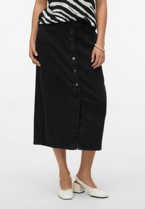 Svart denim midi kjol med framknappar, rak skärning och sidofickor. Kombinerad med en svart och vit mönstrad topp och vita klackskor med blockhäl.
