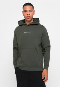 Grøn hoodie med en frontlomme og lille hvid tekst "WEEKEND OFFENDER ADMIT NOTHING." Blødt materiale og afslappet pasform.