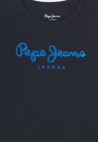 Dunkelmarineblauses Hemd mit dem "Pepe Jeans London"-Logo in Hellblau, verziert mit kleinen, runden Akzenten um den geschwungenen Text.
