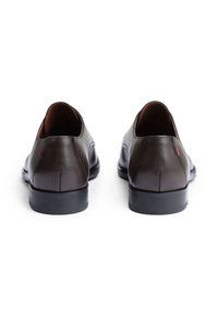 Braune Leder Schuhe mit glänzender Oberfläche, abgerundetem Design, niedrigem Absatz und minimaler Naht; mit einem kleinen roten Akzent am Absatz.