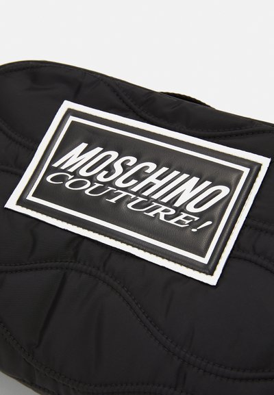 Geantă din material matlasat neagră, având un patch cu un logo proeminent încadrat în alb, cu textul "MOSCHINO COUTURE!" scris cu litere groase negre.