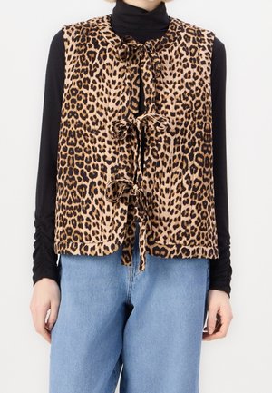 Leopardenmuster-Weste mit drei vorderen Binderverschlüssen, getragen über einem schwarzen Langarmshirt und hellblauen Jeans.