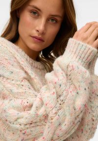 Maglione lavorato a maglia in tonalità pastello con macchie di colore. Presenta una vestibilità ampia con cavi strutturati e polsini a costine. Materiale morbido e caldo.