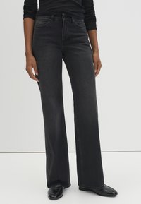 Wide-leg black denim jeans with a high waist, featuring subtle stitching details and a classic five-pocket design. Smooth texture.