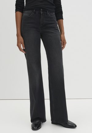 Wijde zwarte denim jeans met een hoge taille, voorzien van subtiele stikdetails en een klassieke vijf-pocketontwerp. Soepele textuur.