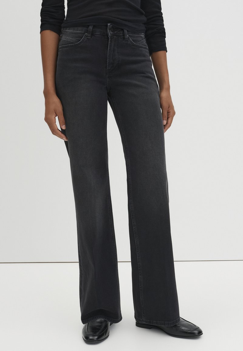 Wide-leg black denim jeans with a high waist, featuring subtle stitching details and a classic five-pocket design. Smooth texture.