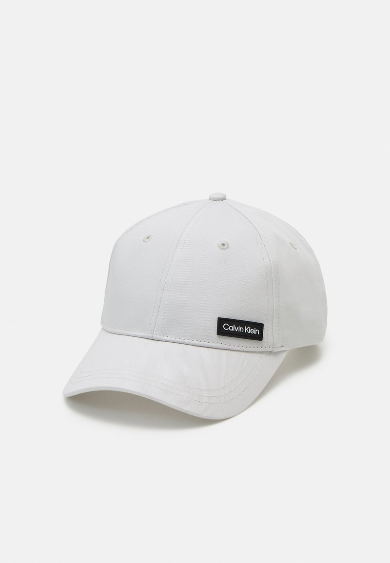 Cappellino da baseball bianco in cotone con corona arrotondata e visiera curva. Presenta un patch con il logo nero di Calvin Klein sulla parte anteriore.