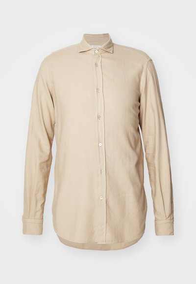 Šviesiai rudos ilgos rankovės marškiniai pagaminti iš lengvos medžiagos, su mygtukų užsegimu priekyje, plati apykakle ir šiek tiek kreivu hemu su subtilia tekstūra.