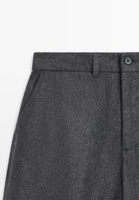 Gray wool trousers featuring a smooth texture, flat front design, side pockets, and a single button closure at the waist.