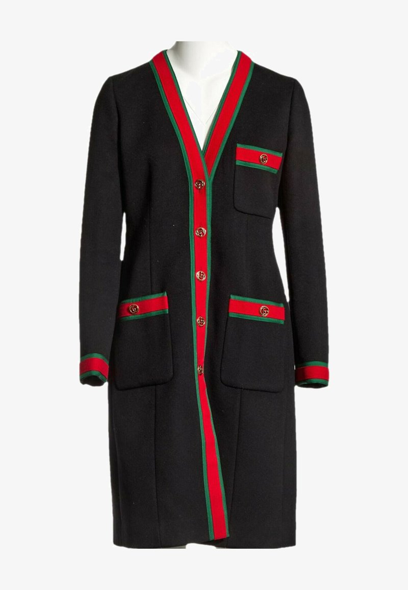 Cardigan long noir avec bordures rouges et vertes au col, aux poignets, aux poches et à la patte de boutonnage, avec des détails de boutons dorés sur le devant et les poches.