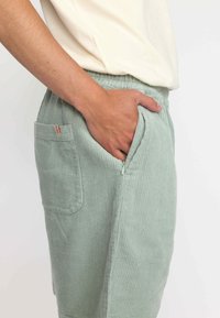 Lichtgroene corduroy short met een gestructureerd oppervlak, elastische tailleband, zijzakken en een klein logo-label op de zak.