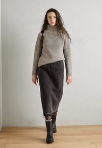 Siv svetrov s polo ovratnikom, v kombinaciji z črno midi krilo z rahlo razfrkanim robom in črnimi gležnjački. Preprost dizajn, teksturirana tkanina.