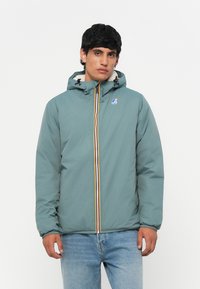 Teal lett jakke med glidelås foran, hette med snorer og flerfarget stripe nedover i midten. Mykt teksturert materiale.