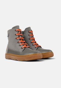 Szare skórzane wysokie buty typu high-top z pomarańczowymi sznurówkami, bocznym zamkiem błyskawicznym i brązową gumową podeszwą. Posiadają teksturowane skórzane panele oraz kontrastowe przeszycia.