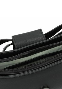 Schwarze Lederhandtasche mit strukturiertem Oberflächen, zwei Reißverschlussfächern und einem grün gefütterten Innenraum. Mit flachem Griff und metallischen Akzenten.