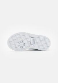 Sole di scarpa in gomma bianca con un motivo a griglia testurizzata. Presenta un logo circolare e un bordo piatto, progettata per offrire presa e stabilità.