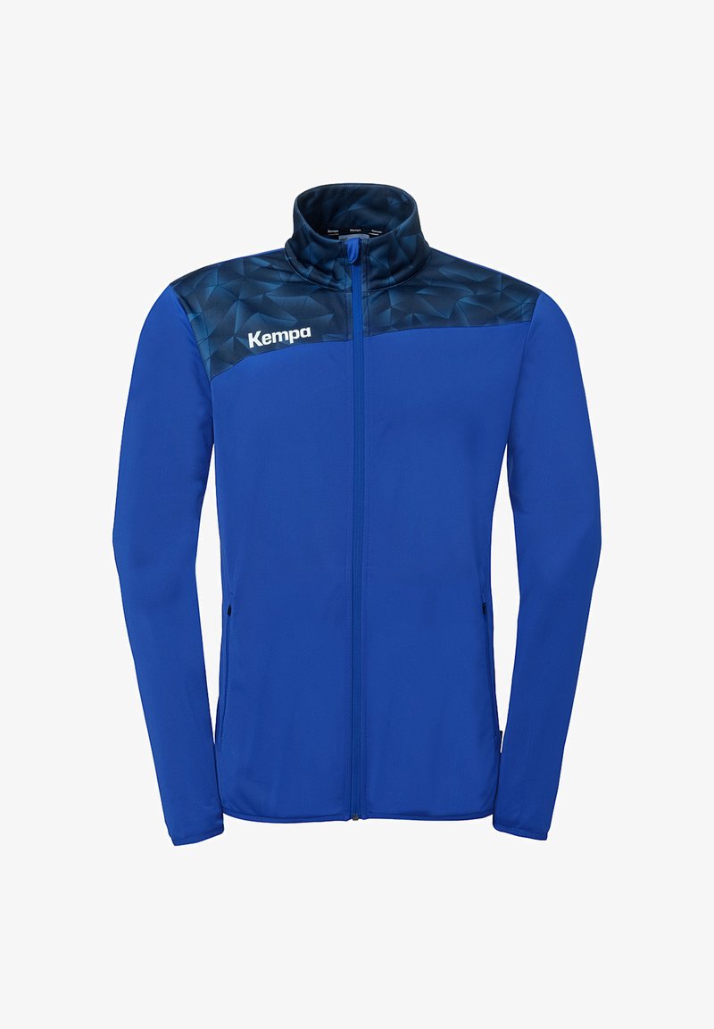 Veste de sport bleue à fermeture éclair intégrale avec un motif géométrique bleu foncé sur les épaules, logo Kempa sur la poitrine gauche, et col montant.