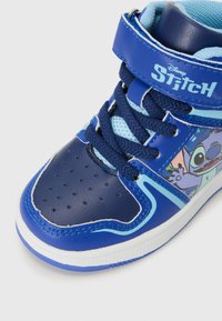 Høye joggesko med en blå syntetisk overdel, perforert tåboks og fargerik Stitch-grafikk på siden. Snøring med borrelås.