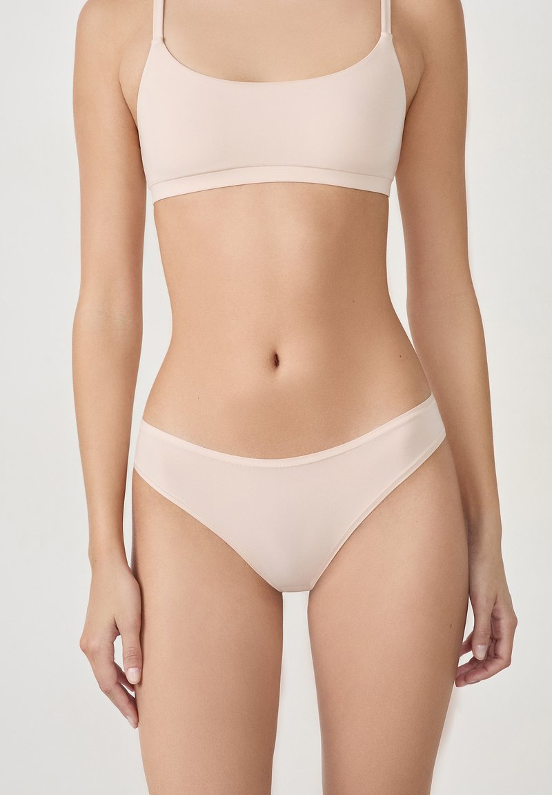 Ensemble de soutien-gorge et culotte seamless rose clair avec des fines bretelles, texture lisse et design minimaliste. Bords élastiques pour un ajustement parfait.