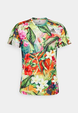 T-shirt de sport Adidas à manches courtes avec un imprimé floral tropical vibrant en tons verts, rouges, blancs, roses et orange sur un fond clair.