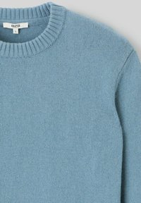 Pull bleu clair avec un col rond tricoté, texture douce et poignets côtelés. L'étiquette indique la taille L et la marque BZB.