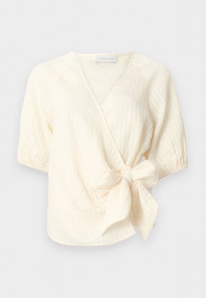 Krémová krátkym rukávom zavinovacia blúzka z textúrovaného materiálu s veľkou bočnou mašľou v páse.