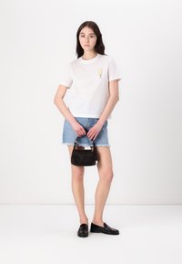 Bela majica s grafiko popsicle, denim krilo s raztrganim robom, črna torbica in črnimi loaferji. Preprost, vsakdanji outfit.