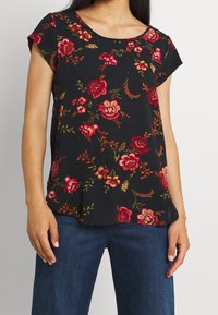 Svart blommig kortärmad topp med röda och orange blommor samt gröna blad. Designad med rund halsringning och avslappnad passform.