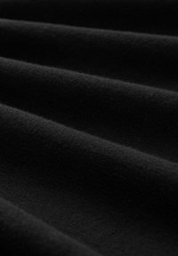 Svart tyg med en mjuk, texturerad yta som visar grunda veck och en slät finish, vilket framhäver dess enhetliga färg och materialkvalitet.