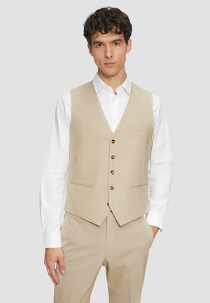 Un gilet beige en tissu texturé, avec un col en V, cinq boutons marron et deux poches, associé à une chemise blanche.