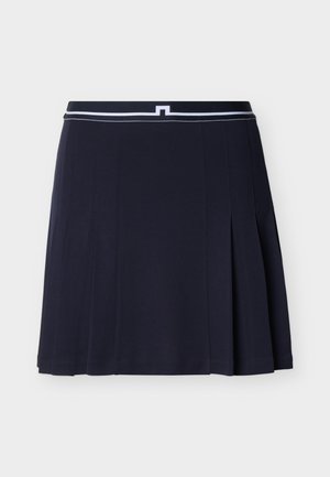 Tengerészkék, pliszírozott szoknya, fehér szegéllyel ellátott derékpánttal és minimalista, függőleges varrásdíszítéssel, világos háttér előtt bemutatva.